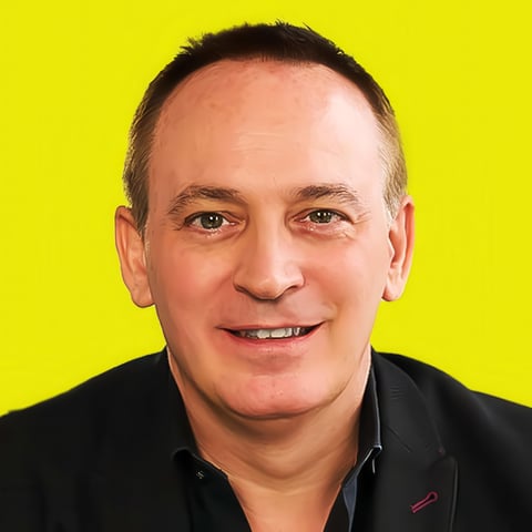 Smiling middle-aged man with dark hair wearing black blazer against bright yellow background